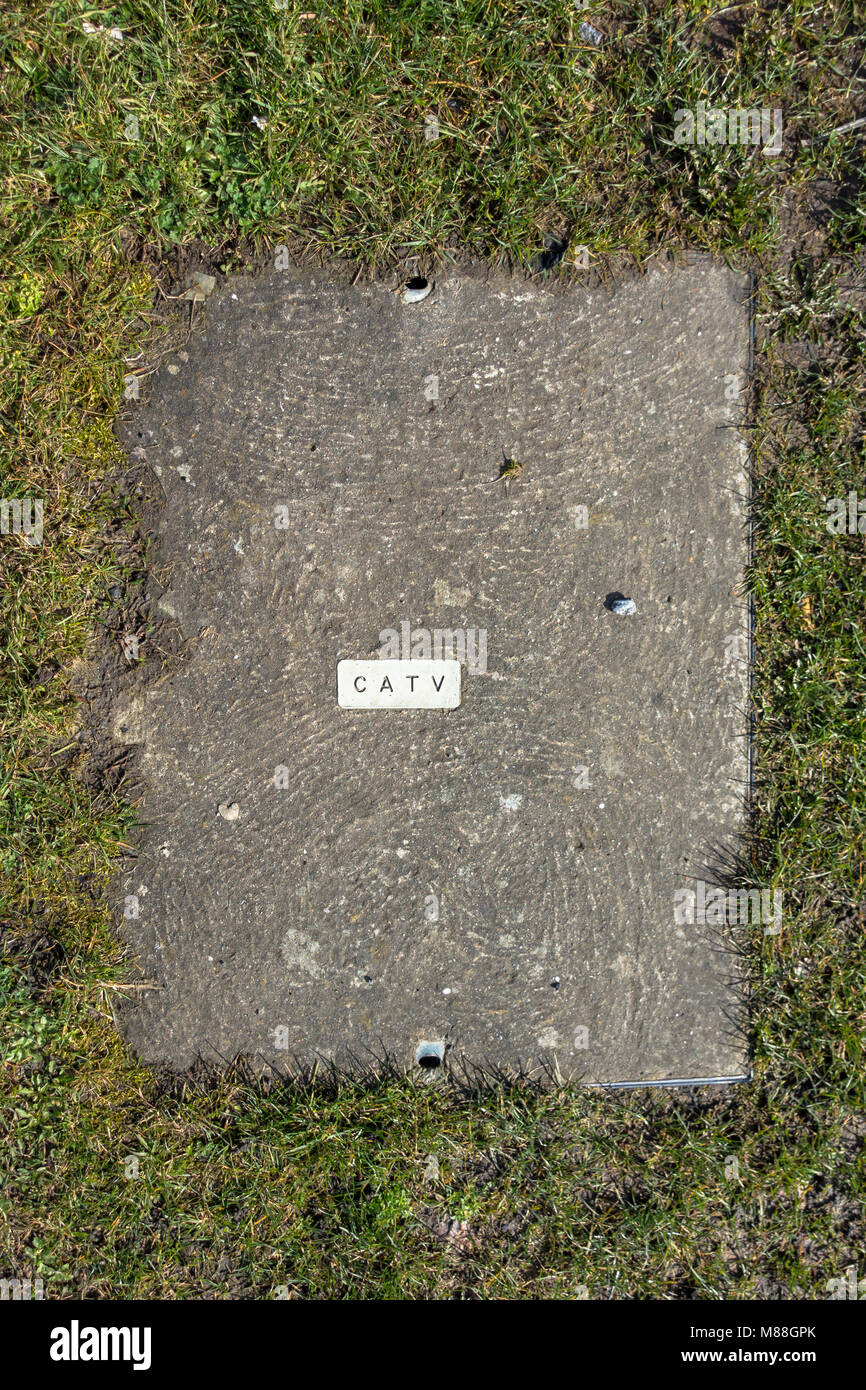 Une dalle d'accès dans un point d'herbe pour donner accès à des ingénieurs de la télévision par câble les câbles. Banque D'Images