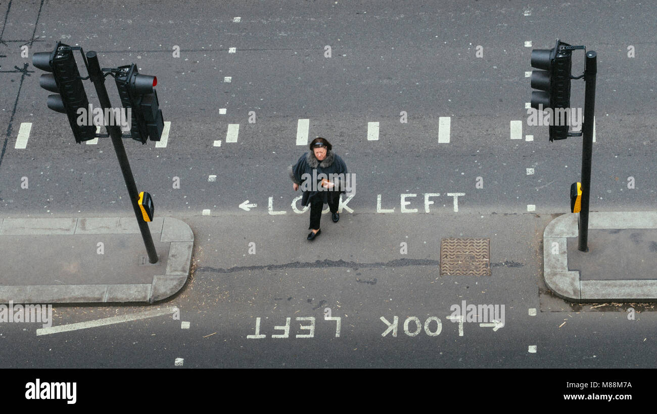 London, UK- Mar 13, 2018 point de vue : vue sur femme seule dans la ville de Londres traversant la rue. Regardez à gauche emblématique et recherchez les signes de droite Banque D'Images