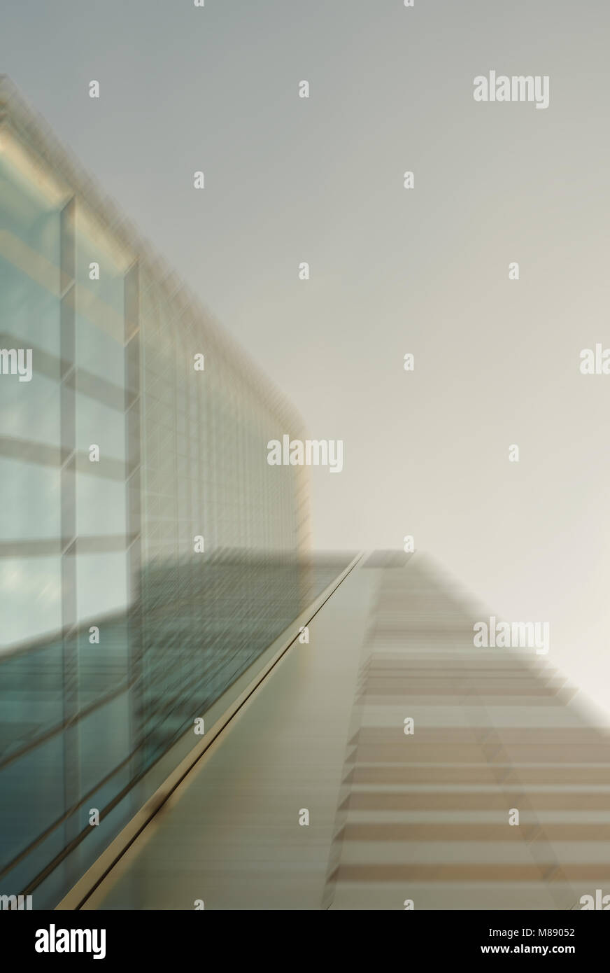 Defocused low angle droit de l'extérieur d'un gratte-ciel moderne en verre contre le ciel dans le quartier des affaires d'une ville Banque D'Images