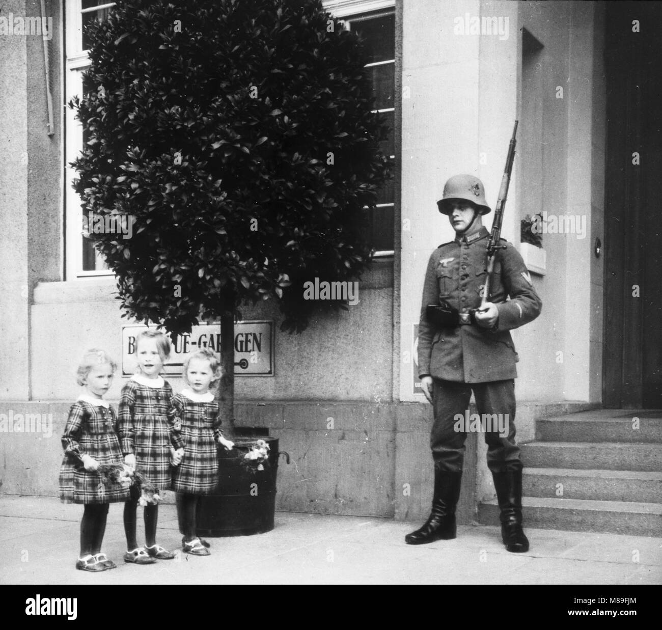 Soldat Nazi gardant un renforcement que trois jeunes filles avec des fleurs d'oeil sur 1938 Banque D'Images