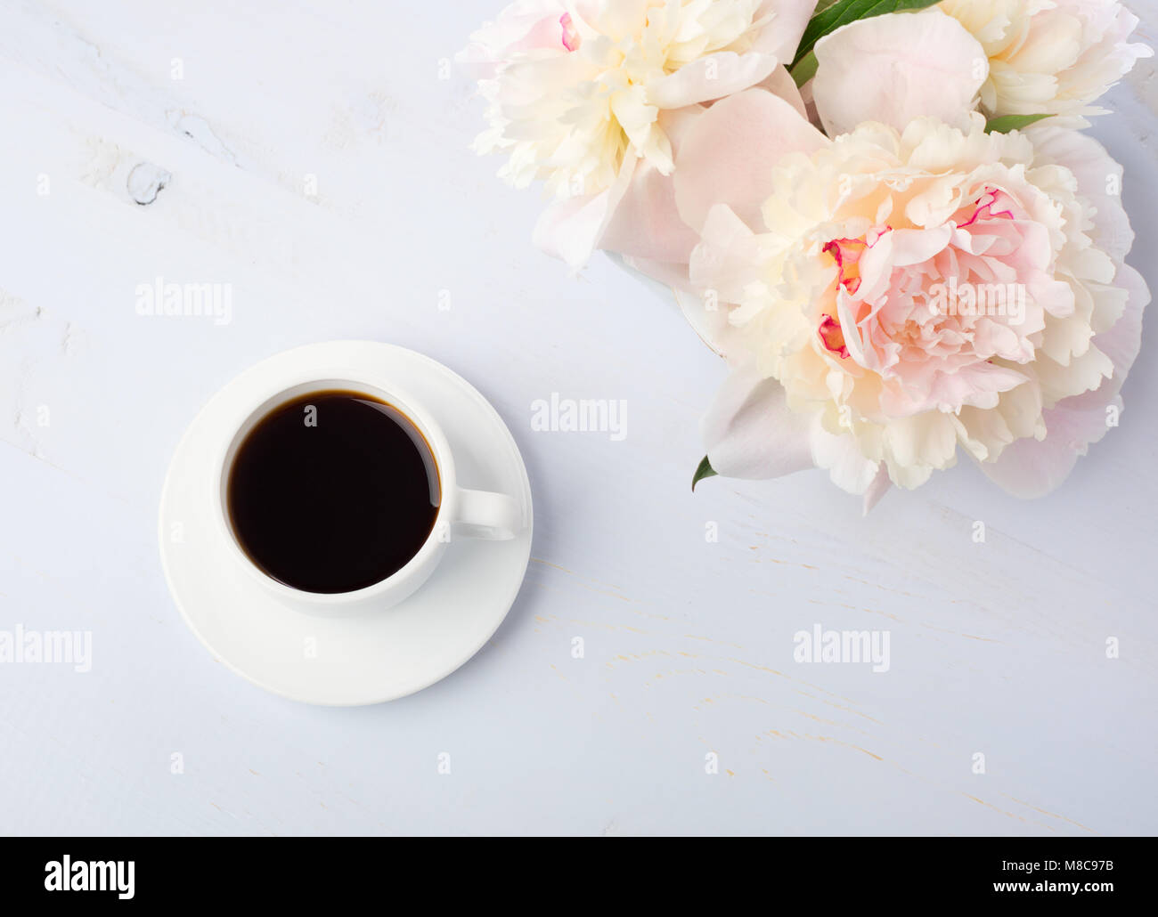 Nature morte à la tasse de café et de fleurs (pivoines) sur table en bois bleu clair. Banque D'Images