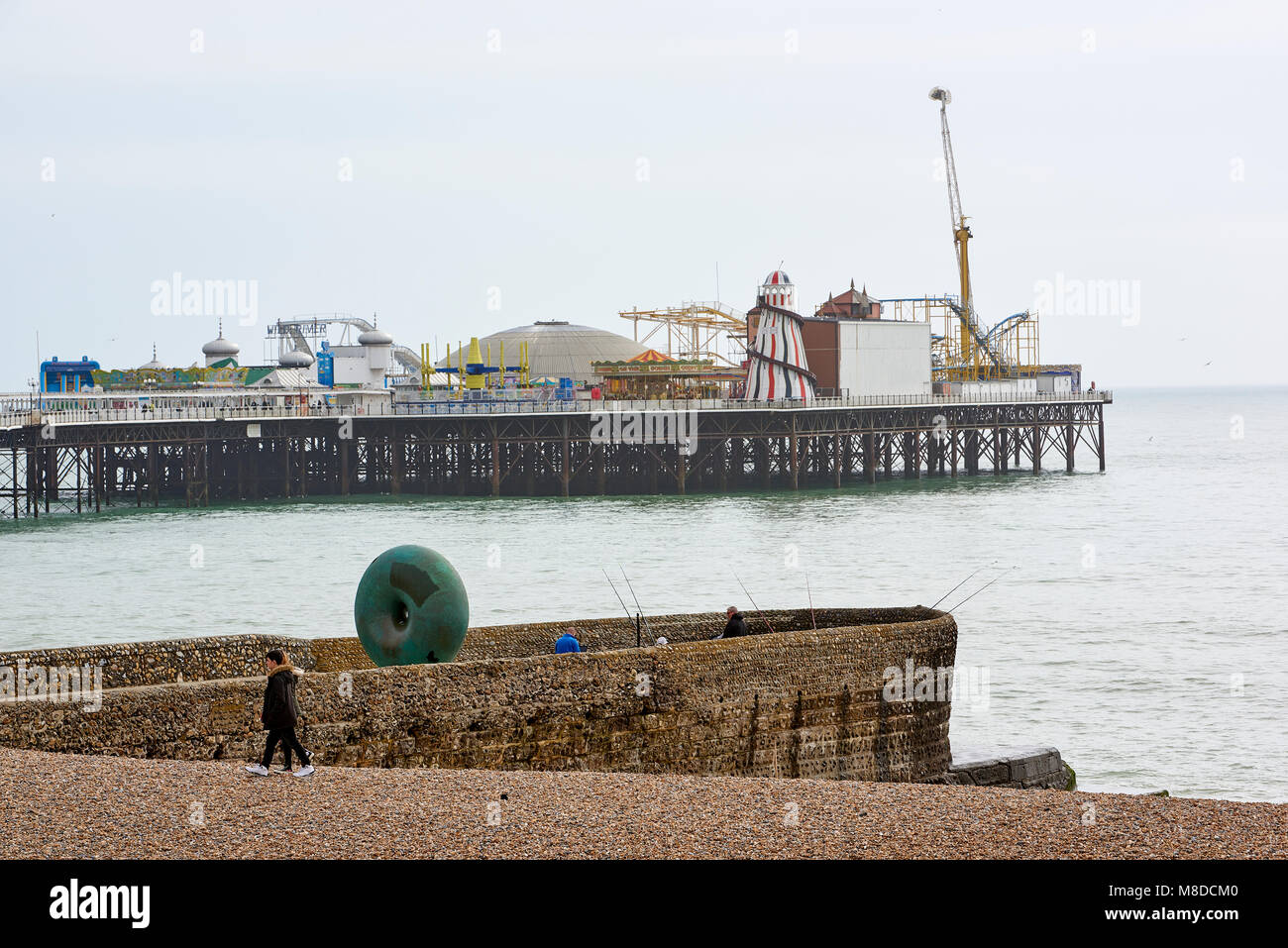 Plan de profil de la jetée de Brighton, avec des gens qui marchent sur la plage au premier plan. Banque D'Images