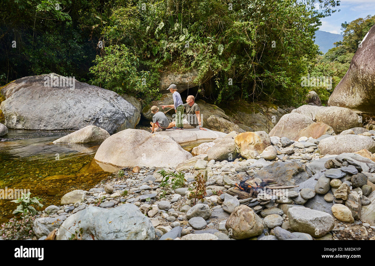 Père et fils se détendre sur les rochers au bord de l'eau, Ventilla, La Paz, Bolivie, Amérique du Sud Banque D'Images