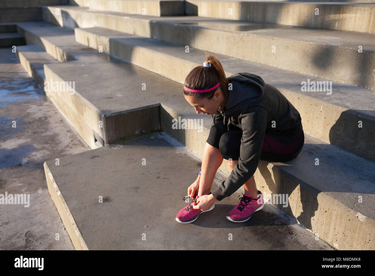 Jeune femme attacher les lacets de chaussures d'entraînement, les étirements des jambes Banque D'Images
