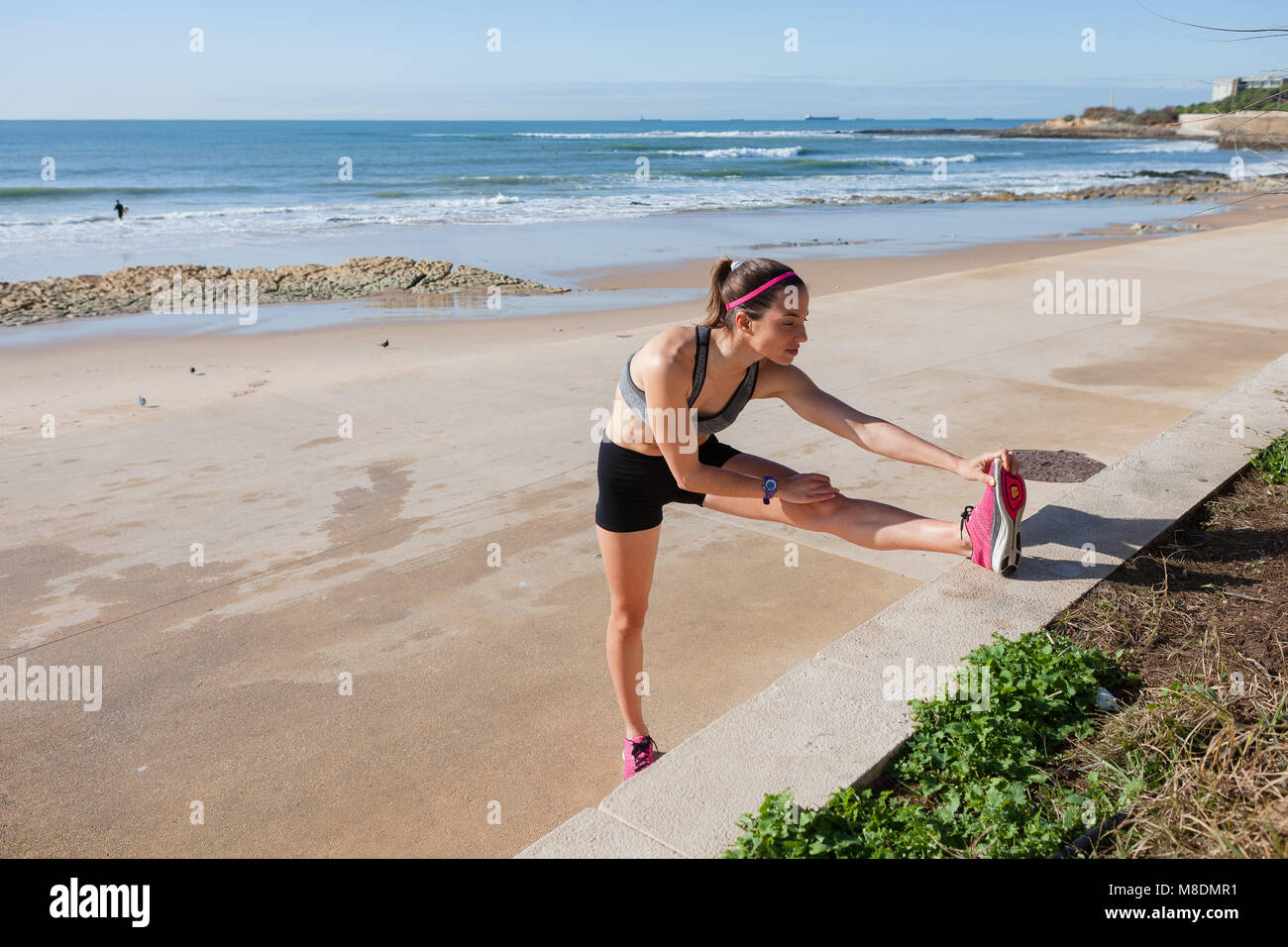 Jeune femme se réchauffer sur la plage, l'étirement des jambes, Carcavelos, Lisboa, Portugal, Europe Banque D'Images
