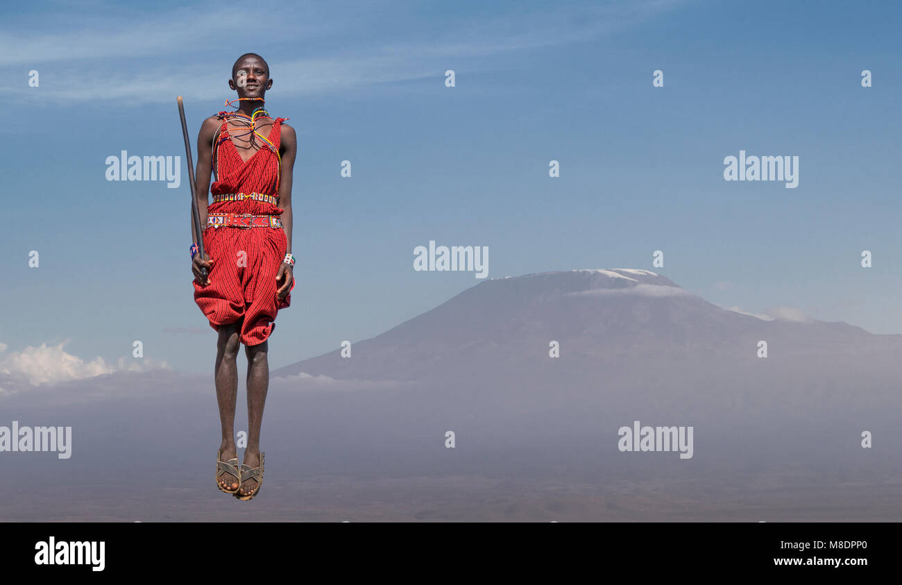 Le Masai homme avec un costume traditionnel de sauter devant le mont Kilimanjaro, Amboseli, Rift Valley, Kenya Banque D'Images