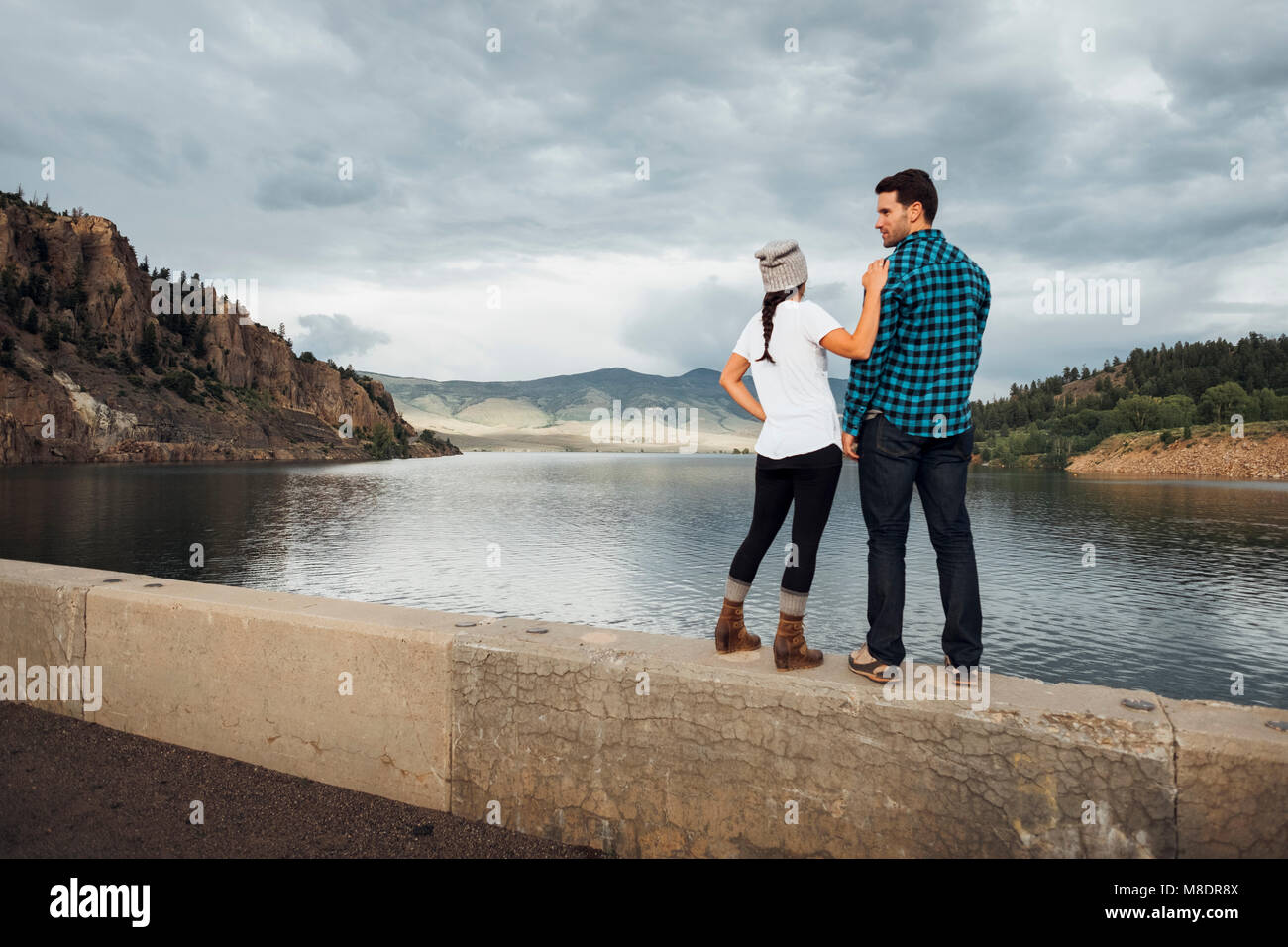 Couple debout sur mur près de Dillon Reservoir, looking at view, vue arrière, Silverthorne, Colorado, USA Banque D'Images