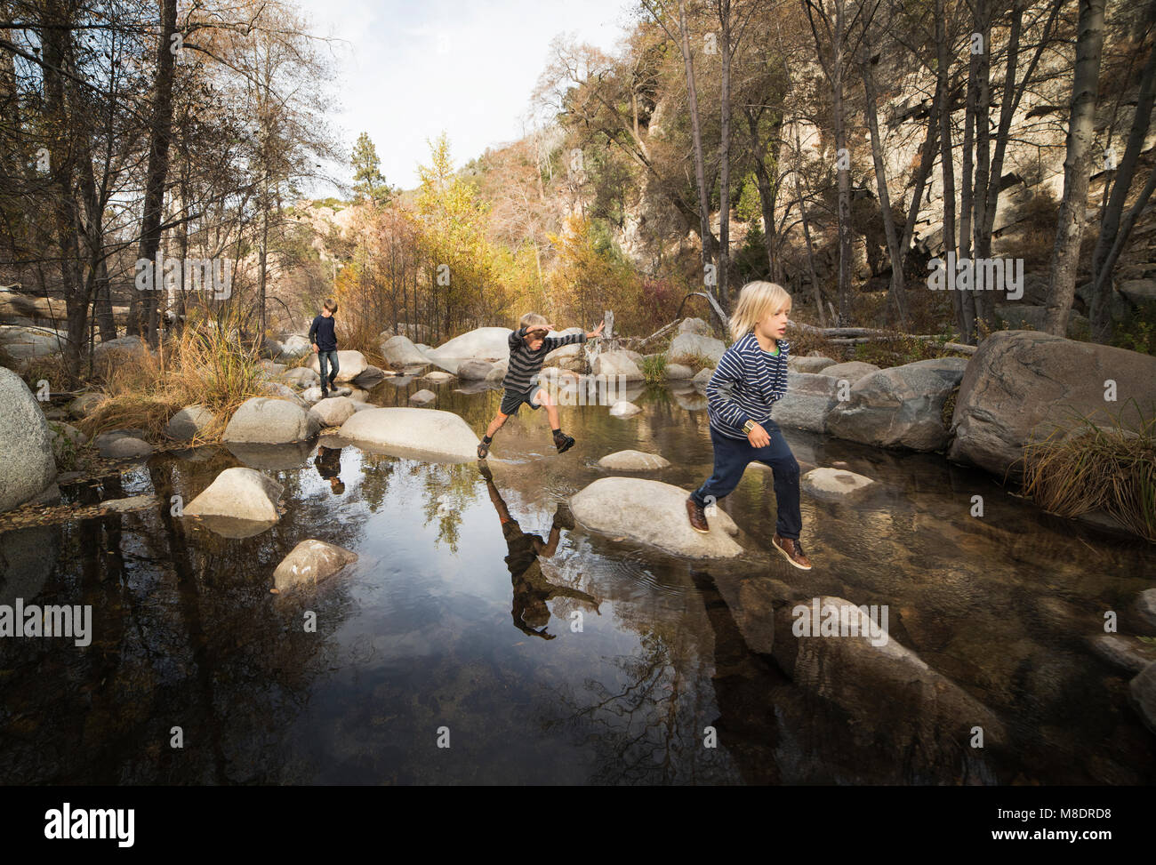 Enfants jouant sur des rochers dans la rivière, lac Arrowhead, California, USA Banque D'Images