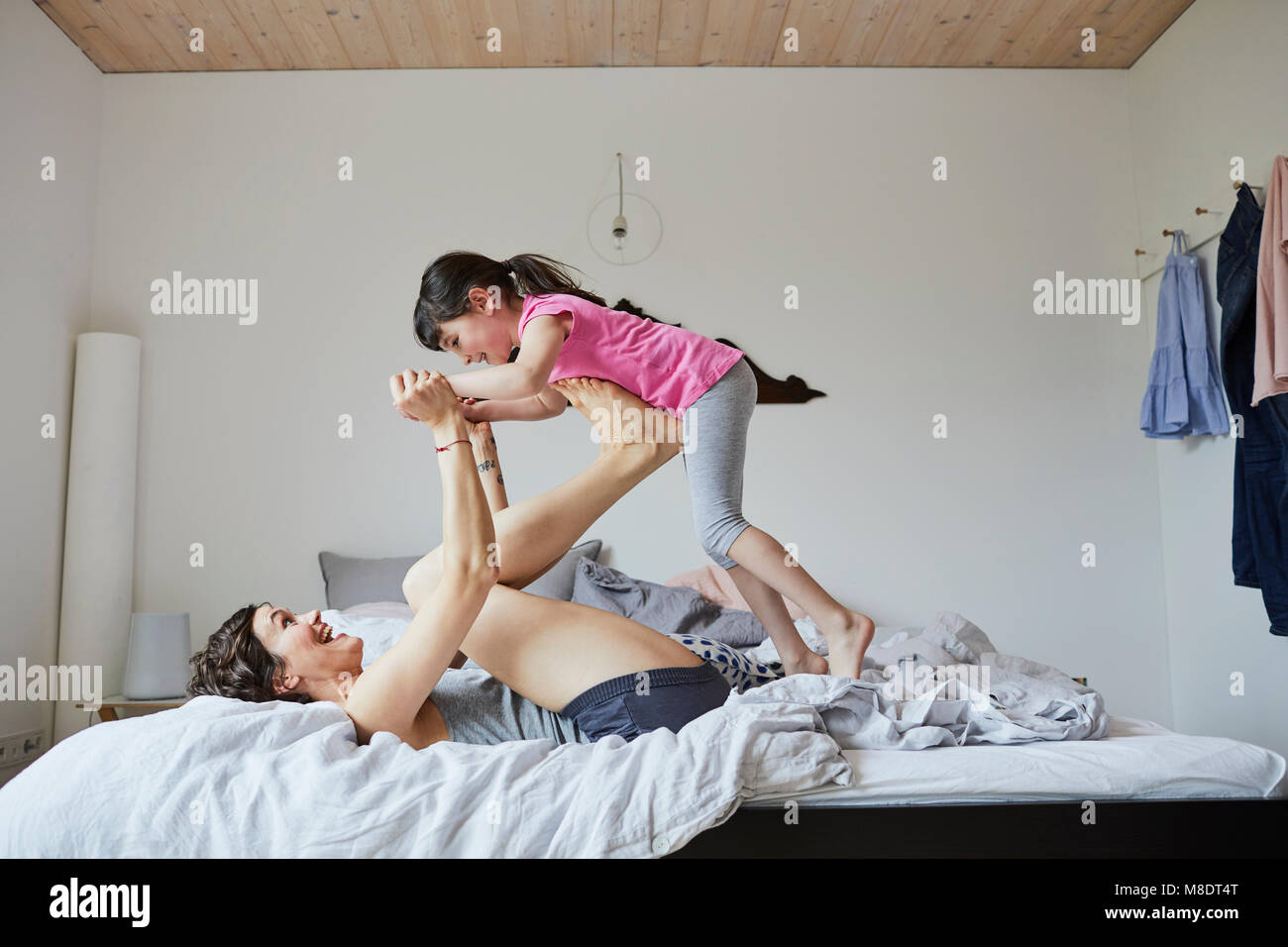 Mère et fille jouer dans la chambre, l'équilibrage de mère fille sur pieds Banque D'Images