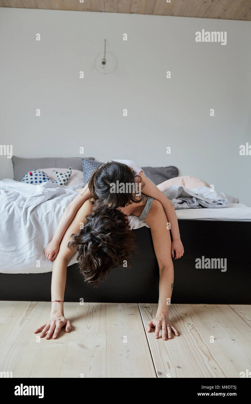 Mother and Daughter lying on bed, daughter lying on mother's back Banque D'Images