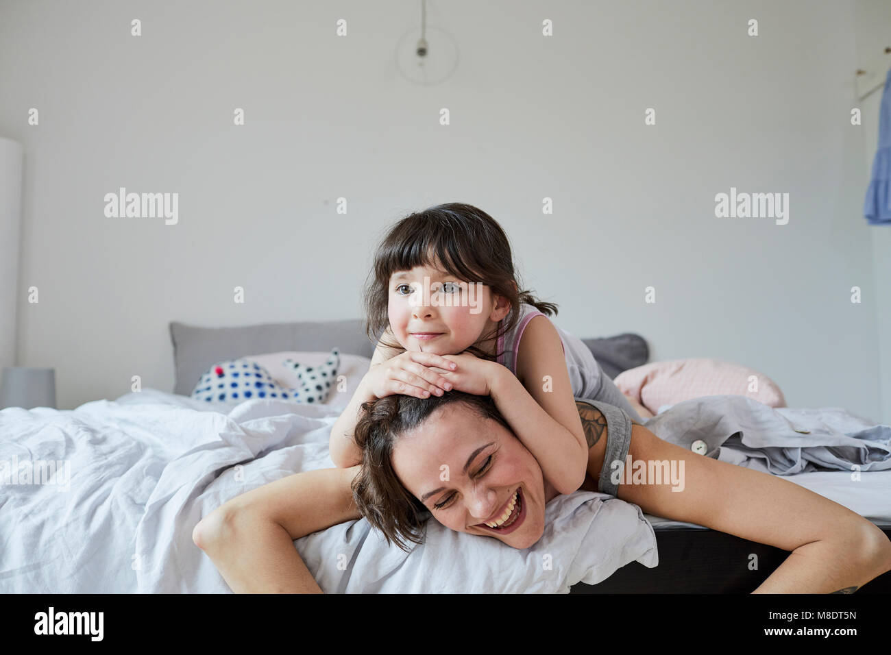 Mother and Daughter lying on bed, daughter lying on mother's back Banque D'Images