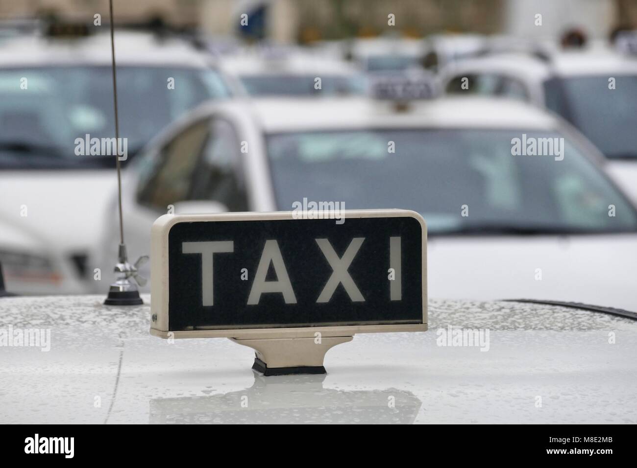 Taxi stationné en lignes clients en attente près de signer sur le toit de voitures Banque D'Images