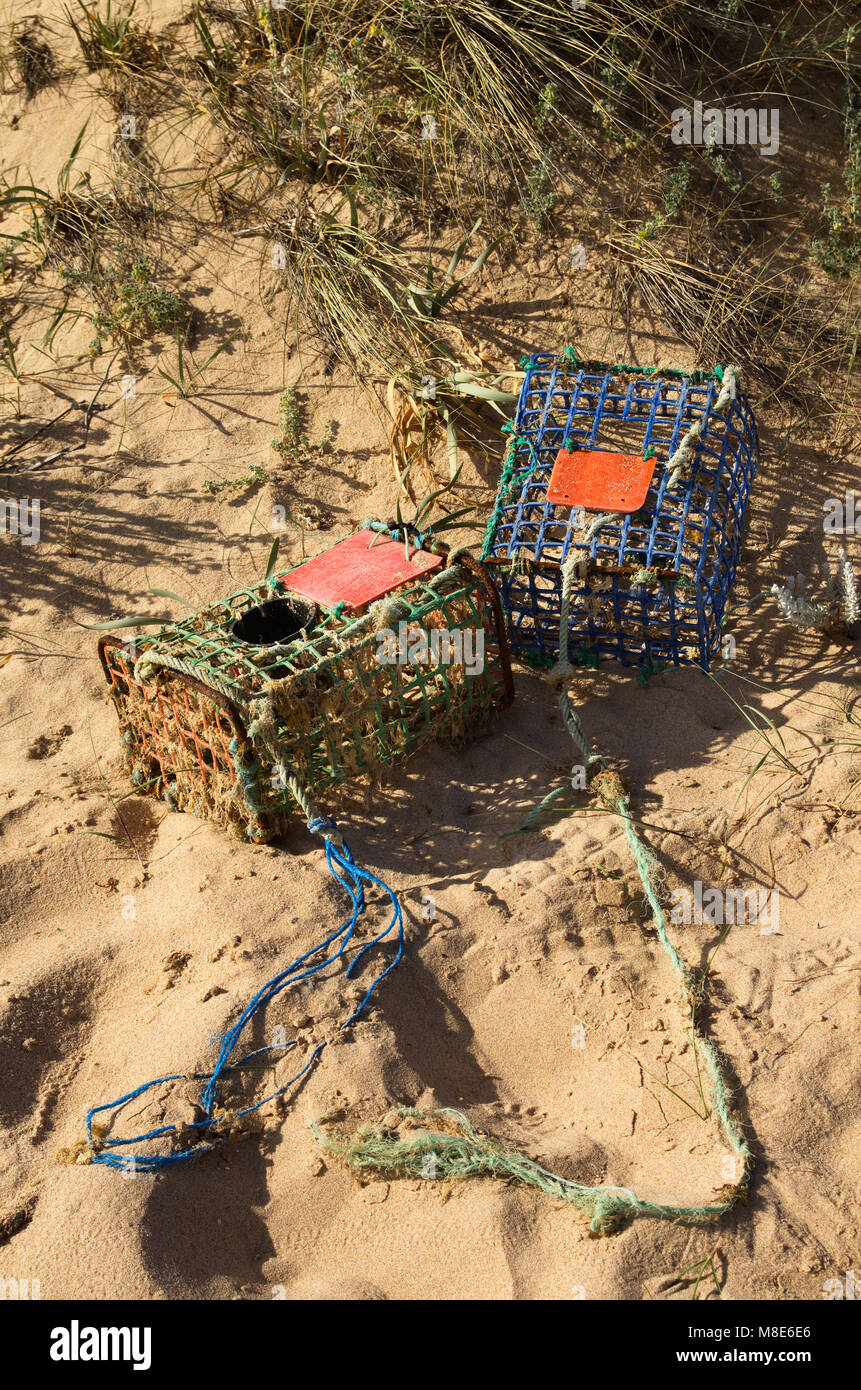 Deux de vieux, fait main, de casiers à crabe emportés par les marées et les vagues dans le sable des dunes. Le fer et les matériaux en plastique de couleur. Vila Nova de Milfo Banque D'Images