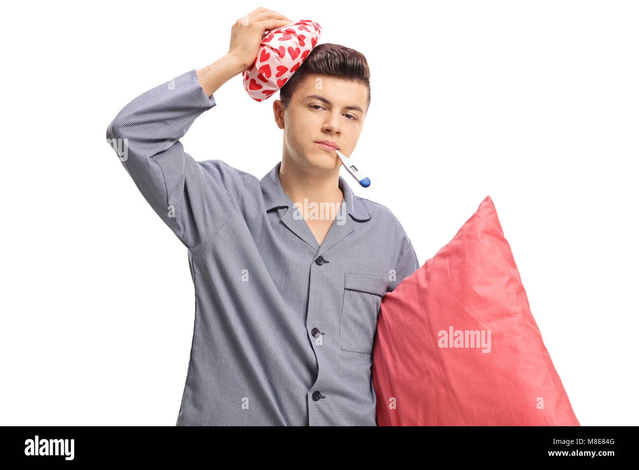 Sick boy in pajamas holding un sac réfrigérant sur la tête et un thermomètre dans la bouche isolé sur fond blanc Banque D'Images