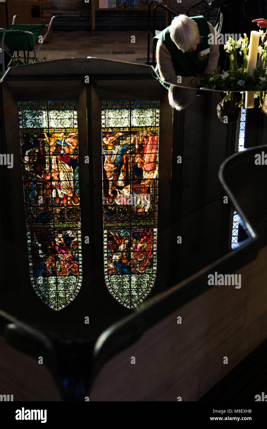 Une femme prend des fleurs à la cathédrale de Salisbury de Salisbury, Wiltshire, Angleterre. Un vitrail reflète dans l'eau de la police. Banque D'Images