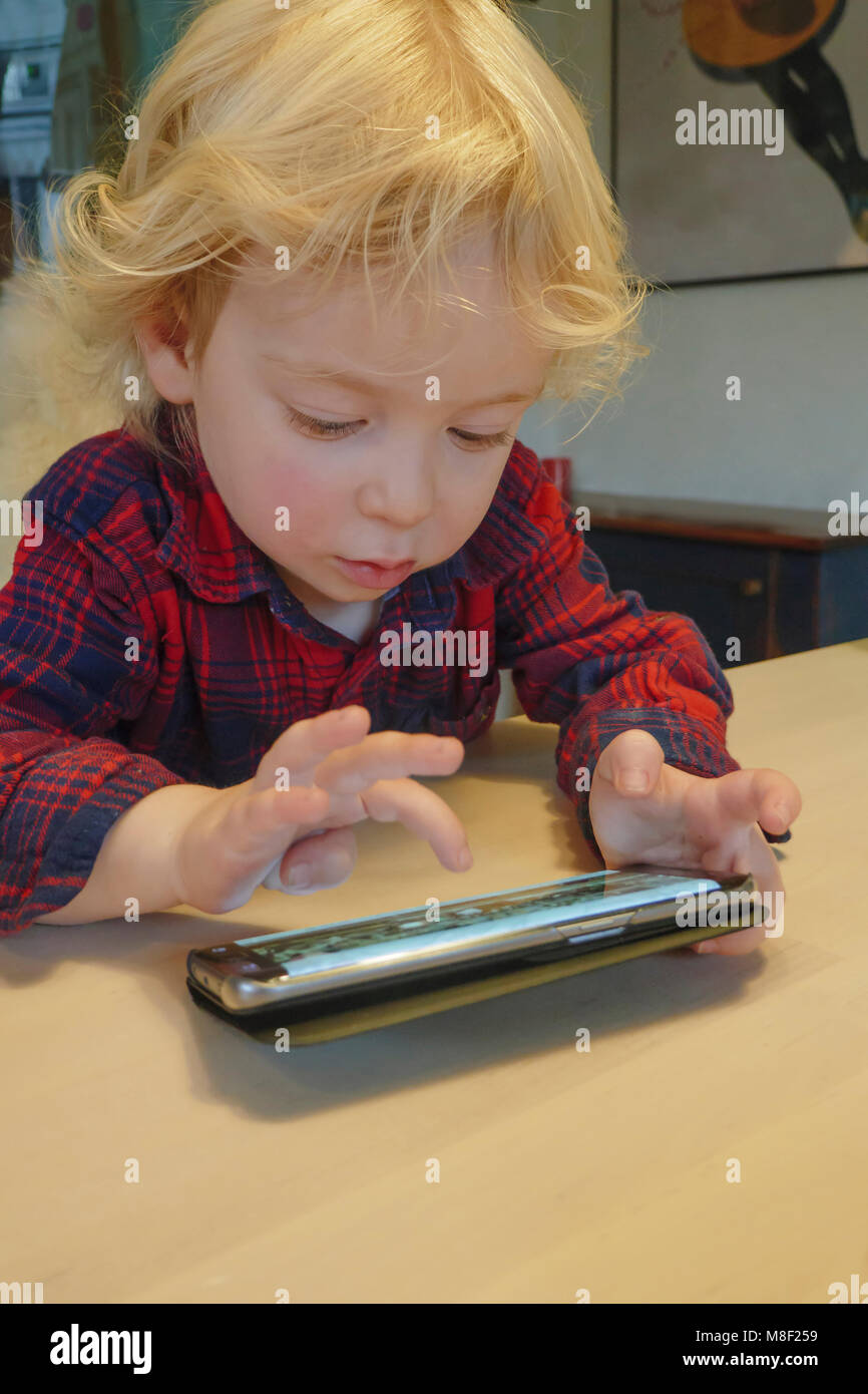 Little Boy (2-3) joue une partie sur smart phone Banque D'Images