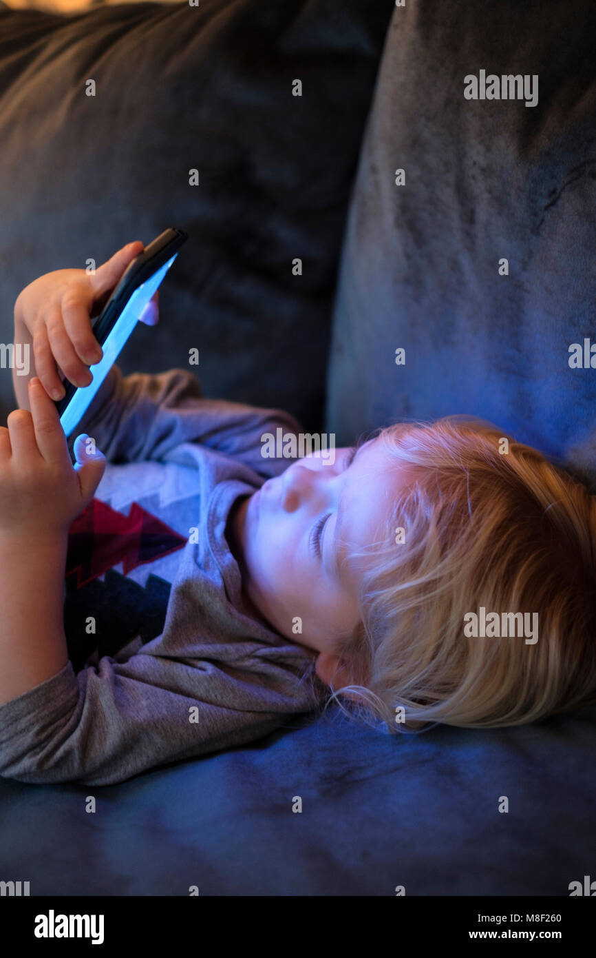 Little Boy (2-3) en position couchée et de cartes sur téléphone intelligent Banque D'Images
