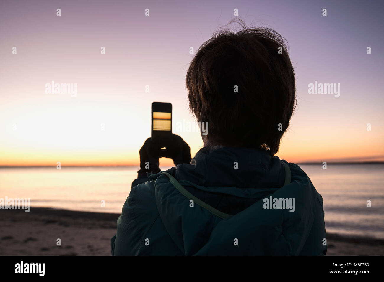 Woman on beach taking photo with smartphone Banque D'Images