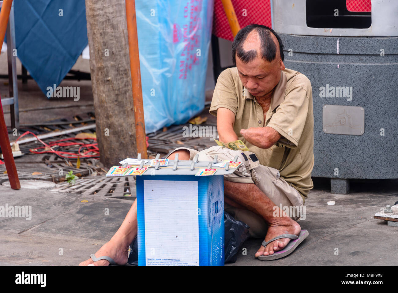 Ci-dessous, un homme amputé du coude, gagne sa vie en vendant des articles sur la rue, Ho Chi Minh City, Vietnam Banque D'Images