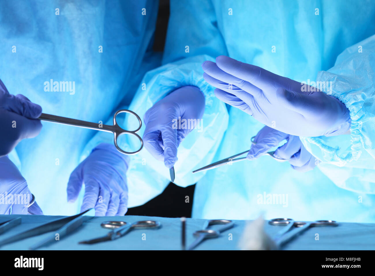 Chirurgiens hands holding surgical scissors et passant le matériel chirurgical, close-up. Soins de santé et vétérinaire concept Banque D'Images