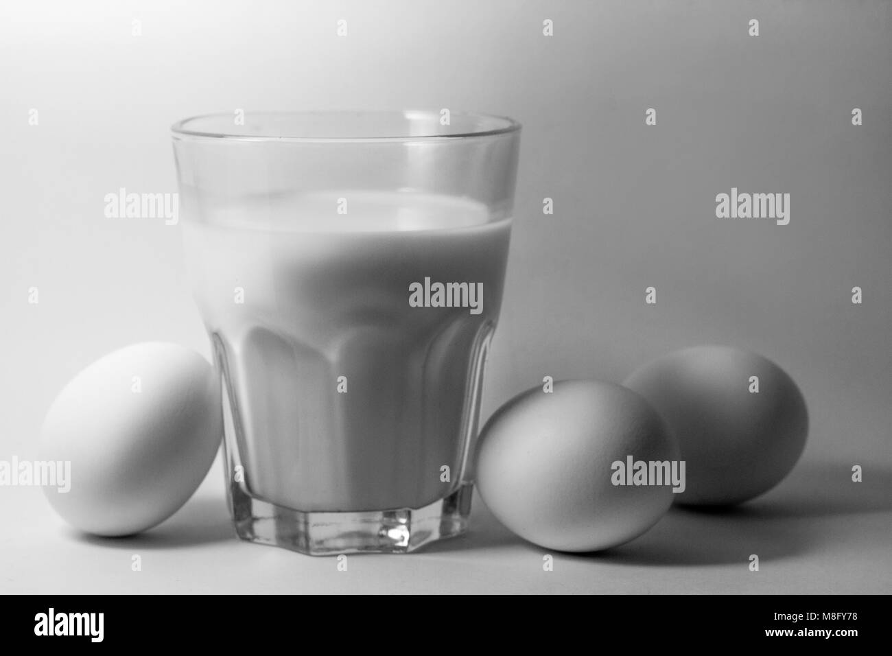 Un verre de lait oeufs sur fond blanc Banque D'Images