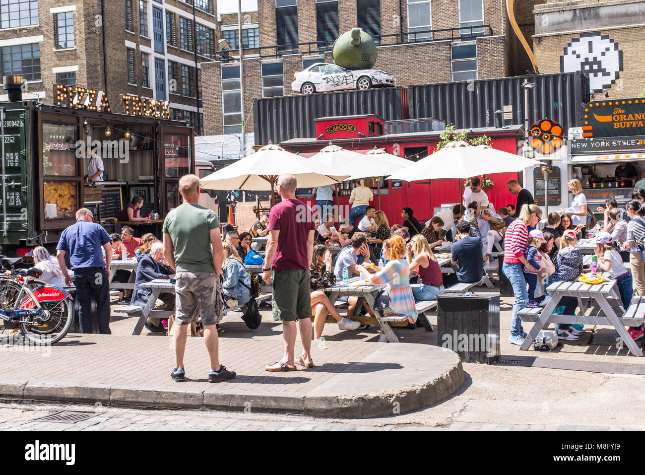 Pop up stands restaurants en plein air avec des gens de manger sur des tables outiside à l'Old Truman Brewery, Ely's Yard, Shoreditch, London, UK Banque D'Images