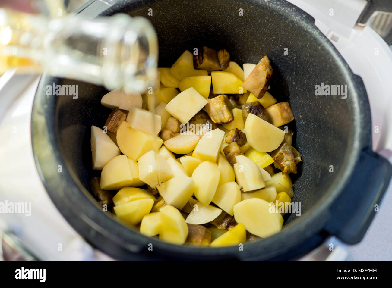 L'huile végétale est versé dans une casserole de pommes de terre Banque D'Images