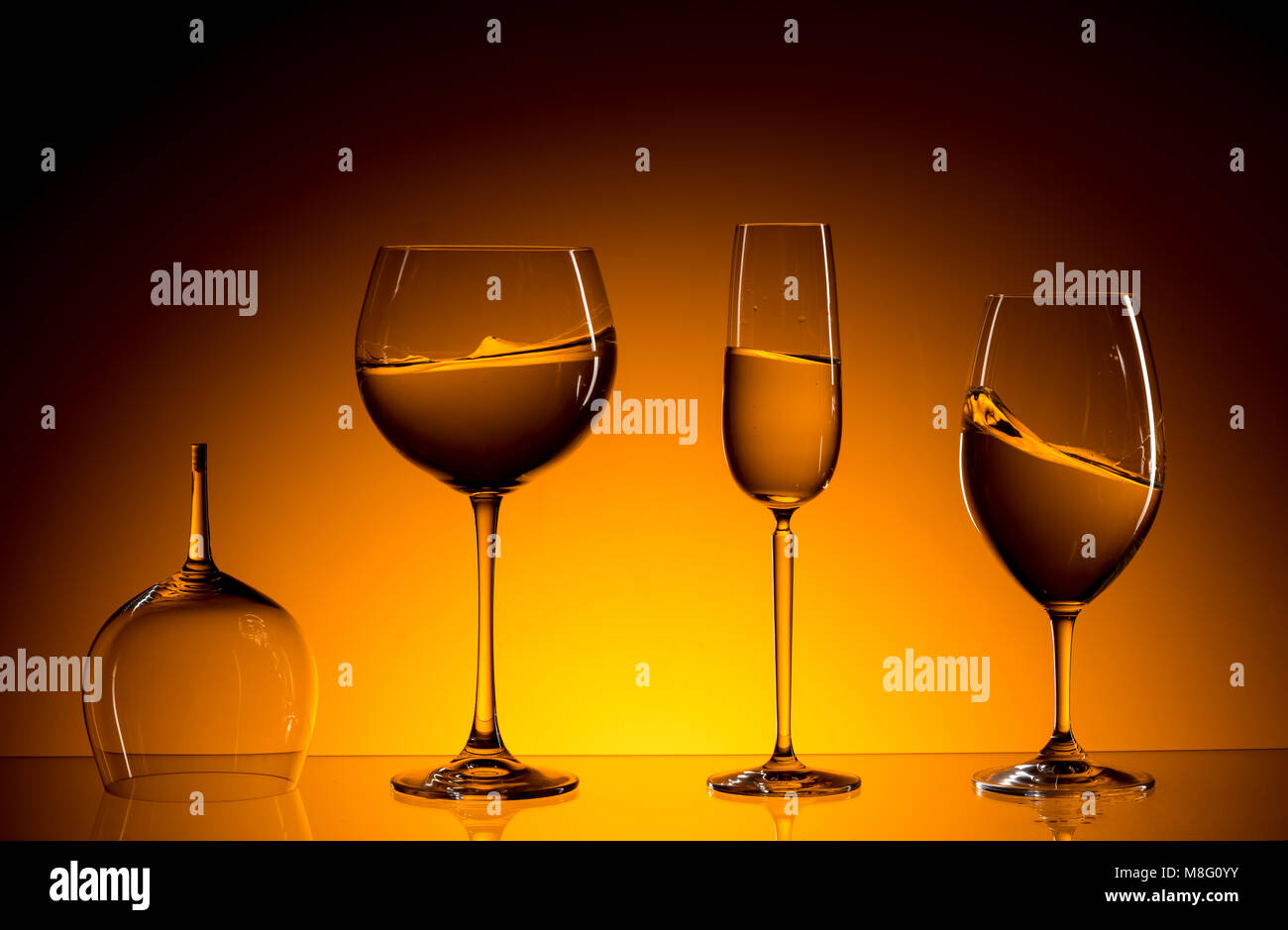 La composition avec trois verres de vin blanc. Un verre est vide et brisée. Fond dégradé jaune et noir. Fine art Photography. Banque D'Images