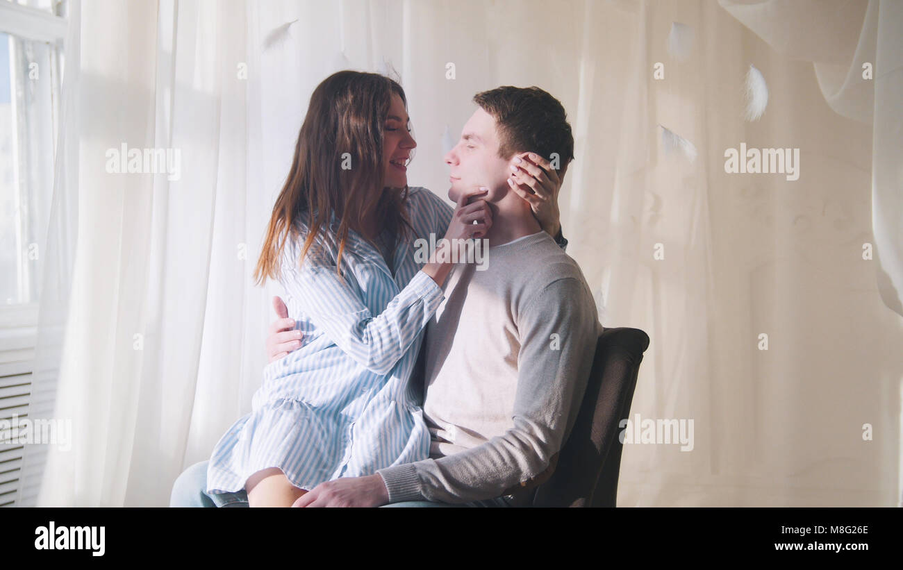 Jeune garçon et une fille s'asseoir près de la fenêtre dans une pièce lumineuse, accolades et embrassades Banque D'Images