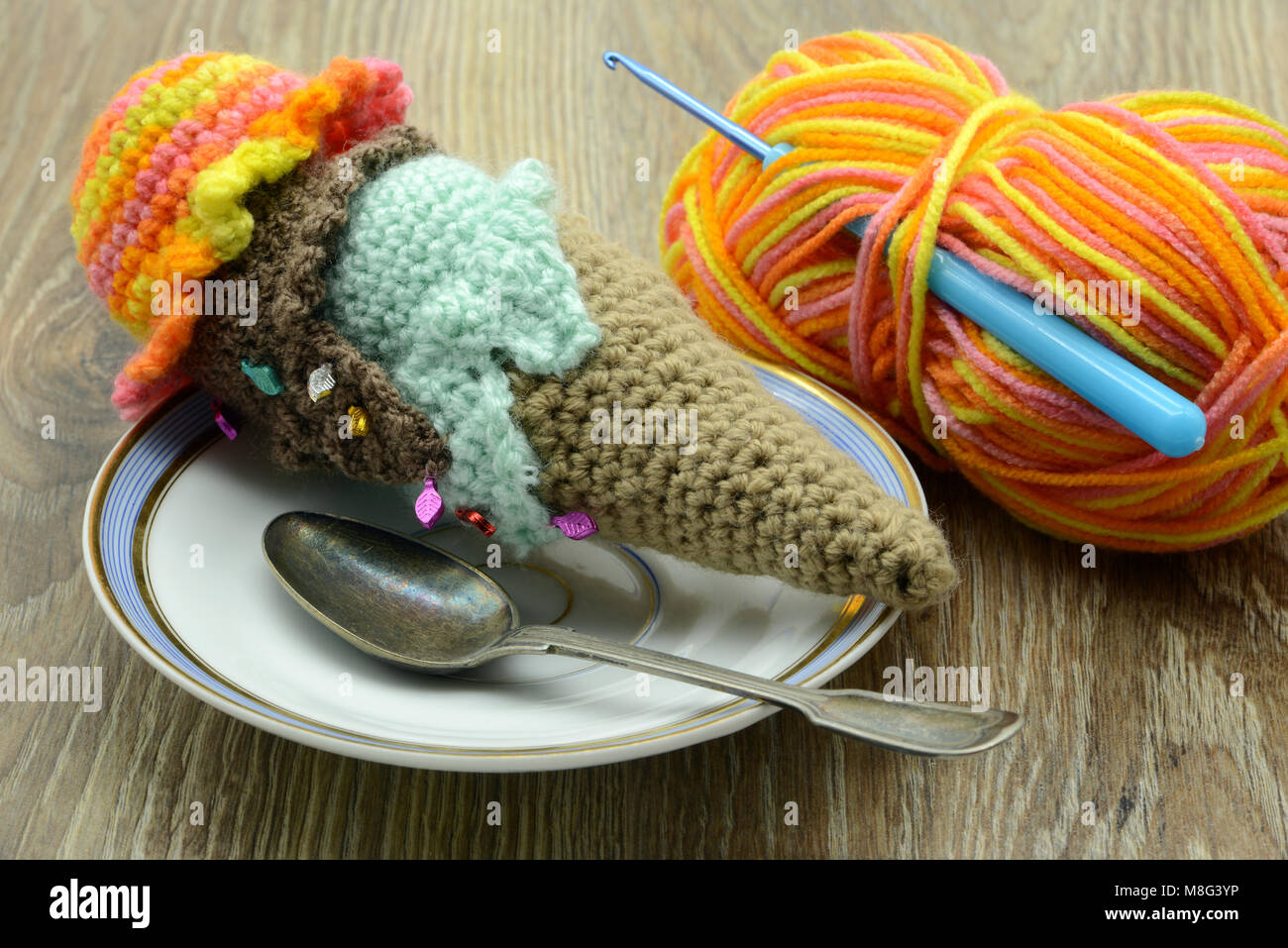 Cornet de crème glacée au crochet avec de la laine de ballons et crochet sur l'arrière-plan de table Banque D'Images