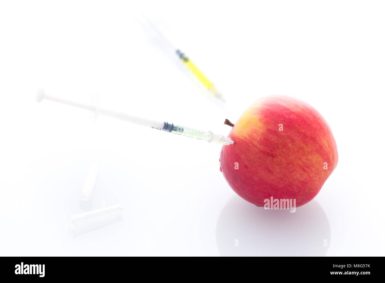 Apple avec les aiguilles et seringues perforé comme un concept de modification de l'alimentation / fond blanc Banque D'Images