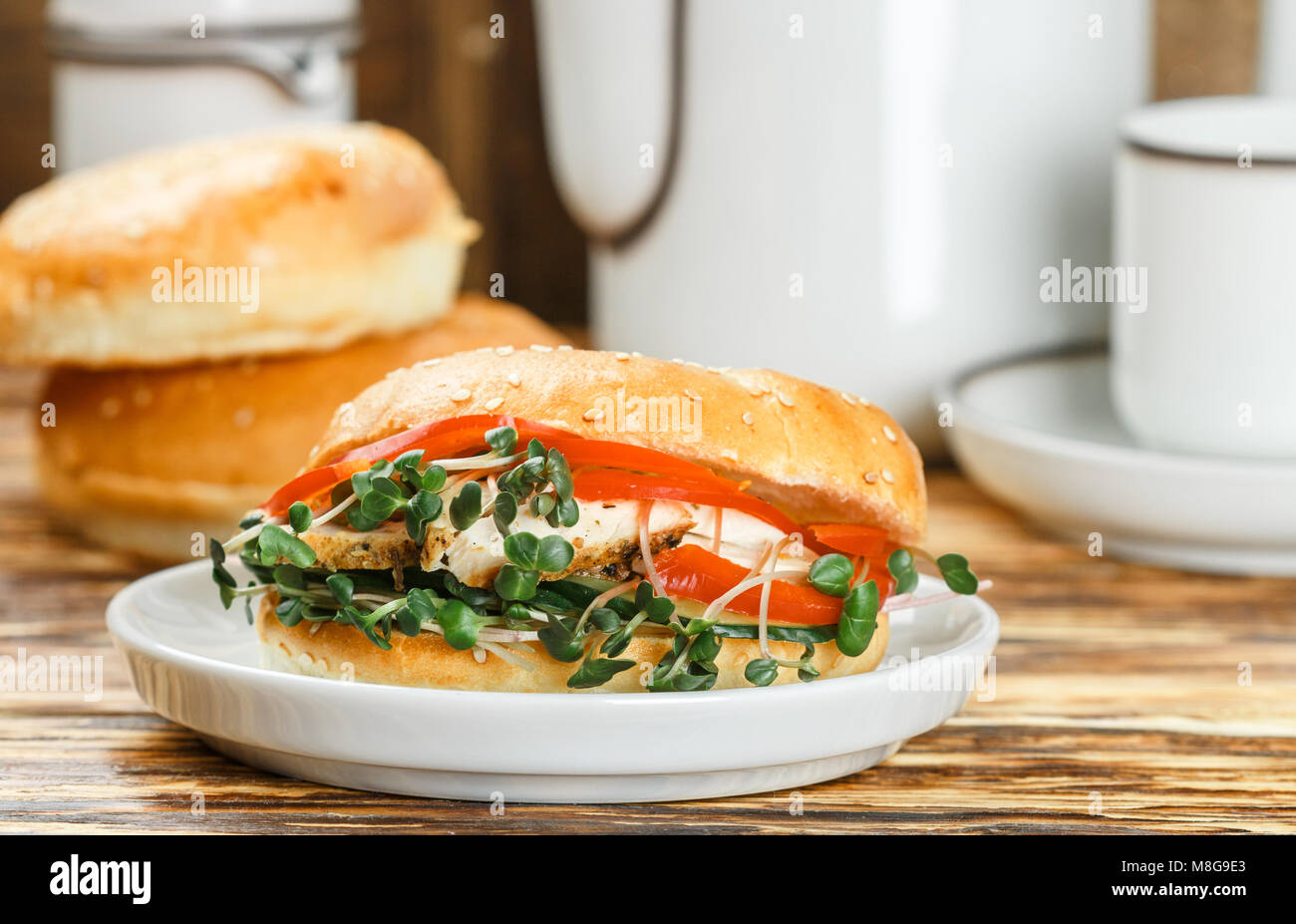 Graines de sésame poulet bagels de grains entiers avec grill, Microgreens, concombre et avocat sur plaque blanche sur fond gris. Petit-déjeuner sain concept . S Banque D'Images