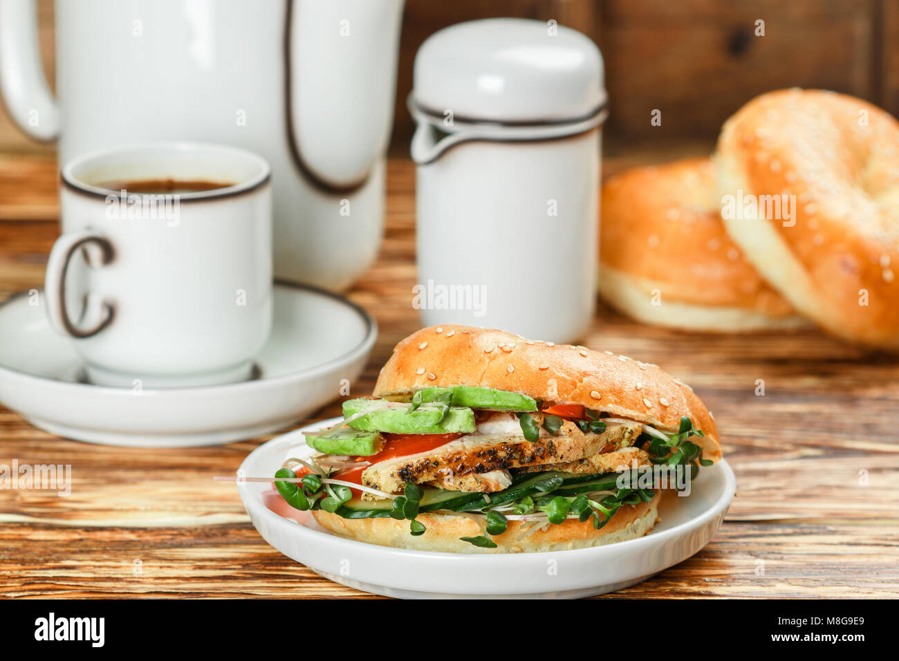 Graines de sésame poulet bagels de grains entiers avec grill, Microgreens, concombre et avocat sur plaque blanche sur fond gris. Petit-déjeuner sain concept . S Banque D'Images