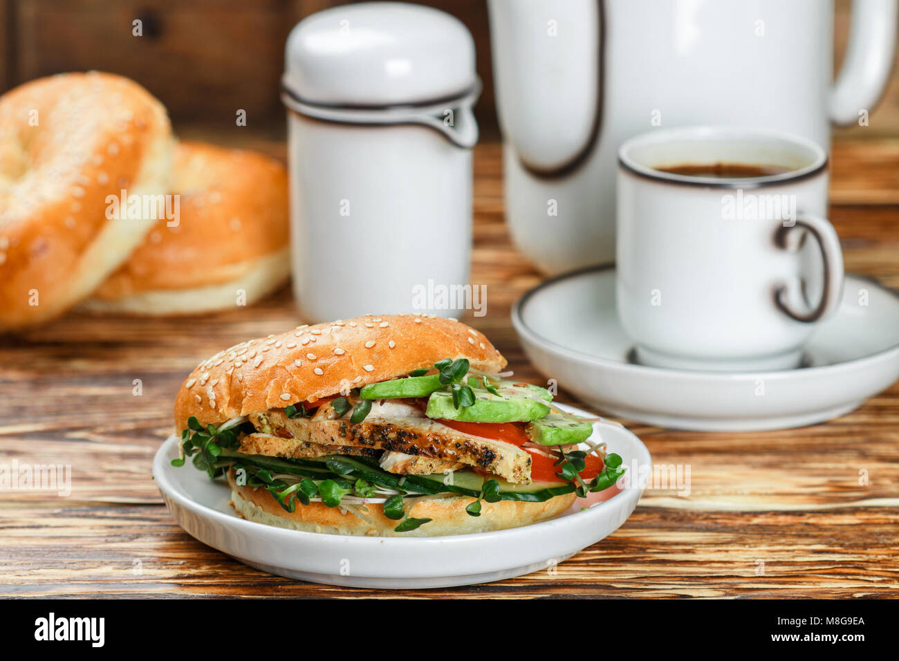 Graines de sésame poulet bagels de grains entiers avec grill, Microgreens, concombre et avocat sur plaque blanche sur fond gris. Petit-déjeuner sain concept . S Banque D'Images