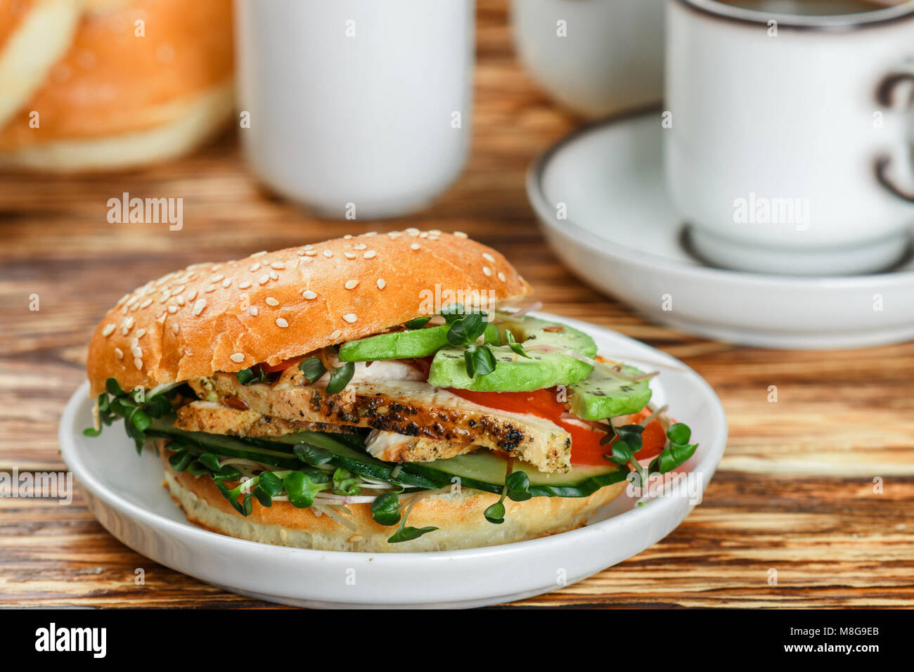Graines de sésame poulet bagels de grains entiers avec grill, Microgreens, concombre et avocat sur plaque blanche sur fond gris. Petit-déjeuner sain concept . S Banque D'Images