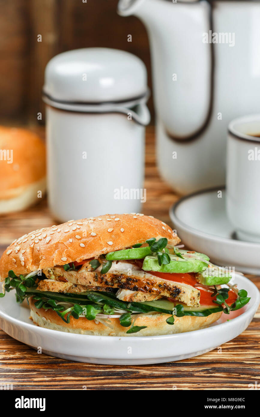 Graines de sésame poulet bagels de grains entiers avec grill, Microgreens, concombre et avocat sur plaque blanche sur fond gris. Petit-déjeuner sain concept . S Banque D'Images
