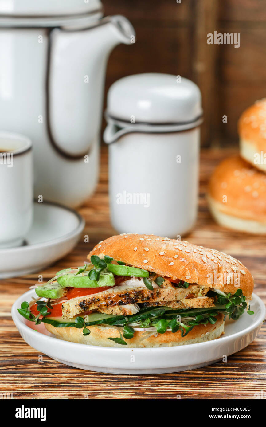 Graines de sésame poulet bagels de grains entiers avec grill, Microgreens, concombre et avocat sur plaque blanche sur fond gris. Petit-déjeuner sain concept . S Banque D'Images