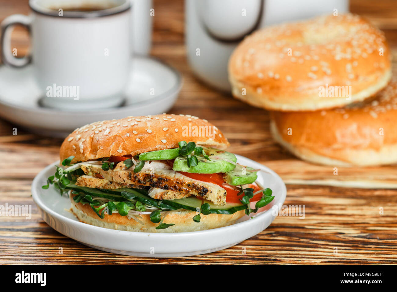 Graines de sésame poulet bagels de grains entiers avec grill, Microgreens, concombre et avocat sur plaque blanche sur fond gris. Petit-déjeuner sain concept . S Banque D'Images