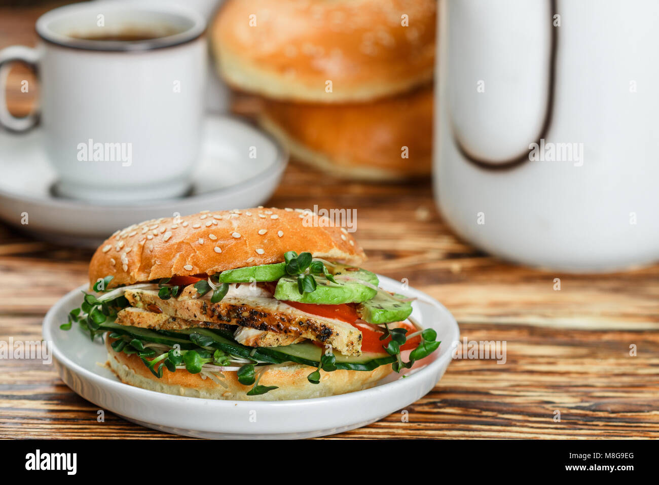 Graines de sésame poulet bagels de grains entiers avec grill, Microgreens, concombre et avocat sur plaque blanche sur fond gris. Petit-déjeuner sain concept . S Banque D'Images