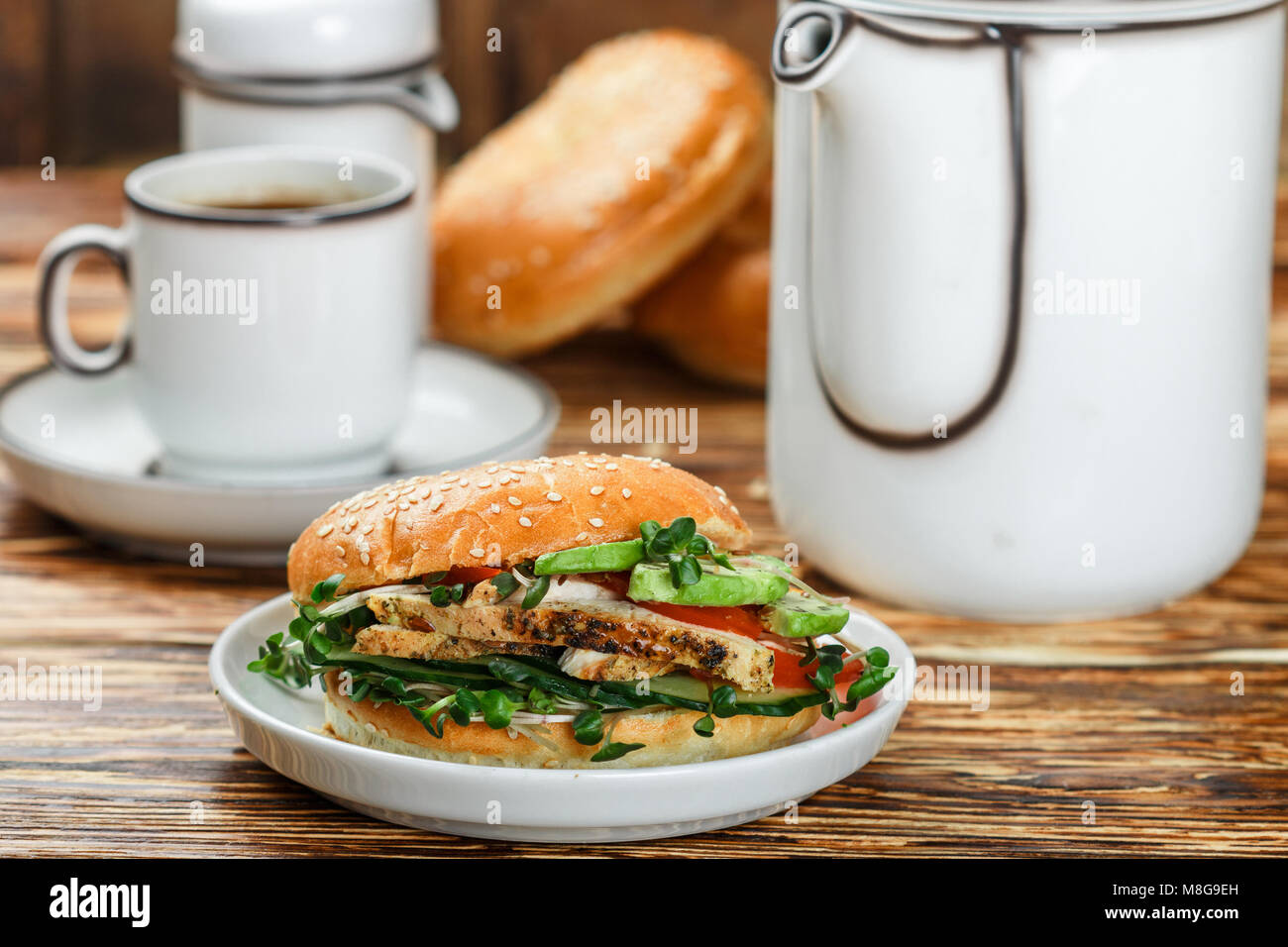 Graines de sésame poulet bagels de grains entiers avec grill, Microgreens, concombre et avocat sur plaque blanche sur fond gris. Petit-déjeuner sain concept . S Banque D'Images