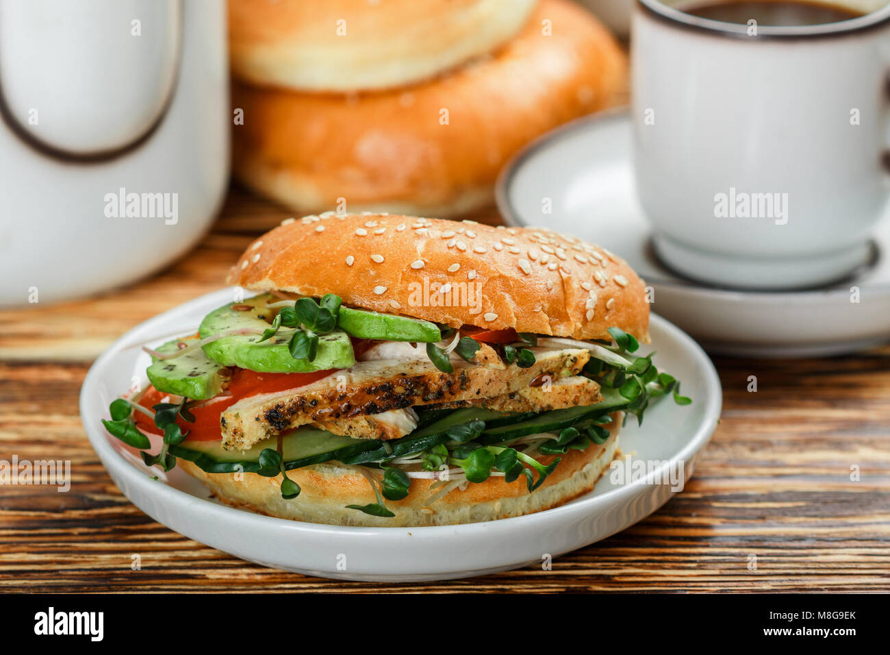 Graines de sésame poulet bagels de grains entiers avec grill, Microgreens, concombre et avocat sur plaque blanche sur fond gris. Petit-déjeuner sain concept . S Banque D'Images