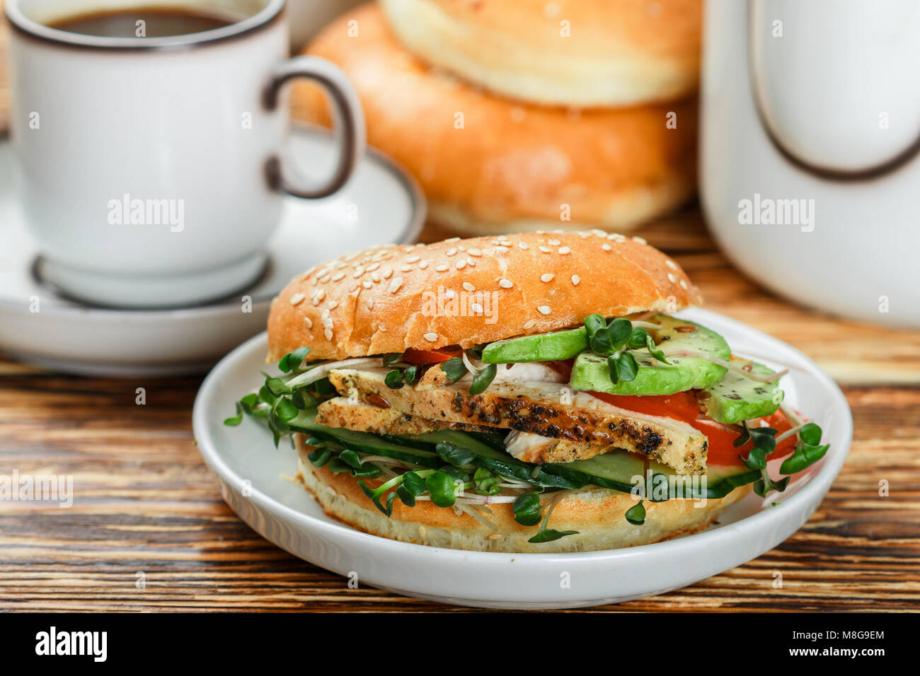 Graines de sésame poulet bagels de grains entiers avec grill, Microgreens, concombre et avocat sur plaque blanche sur fond gris. Petit-déjeuner sain concept . S Banque D'Images