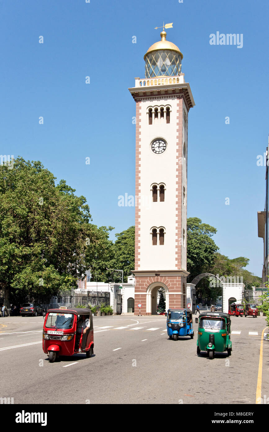 Le vieux phare de Colombo sur une journée ensoleillée avec ciel bleu et 3 trois Tuk Tuks voyageant le long de la route avant-plan. Banque D'Images