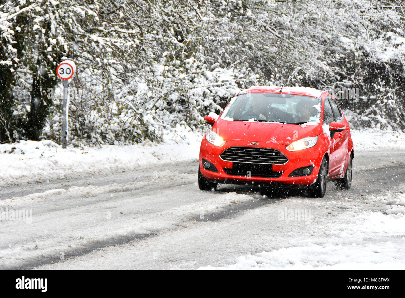 Ford voiture rouge conduite le long 30mph pays couvert de neige en hiver, la route de la création de neige Paysage de neige scène toile Essex England UK Banque D'Images