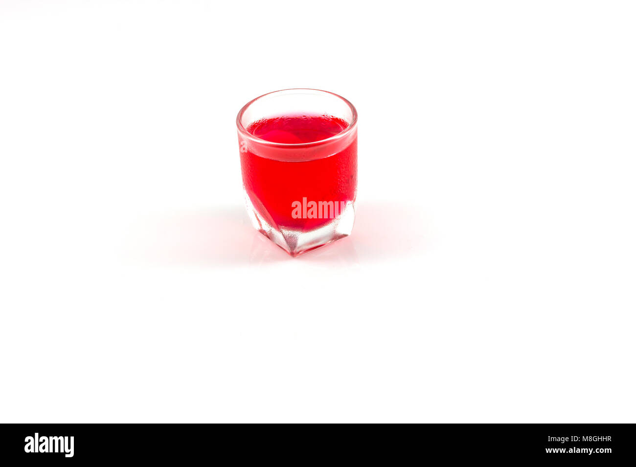 Un verre de l'eau rouge isoler en fond blanc Banque D'Images