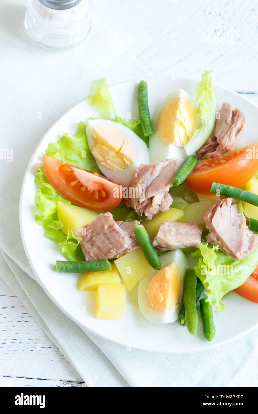 Salade niçoise au thon, oeufs, pommes de terre, haricots verts et tomates. Salade niçoise traditionnelle bleu sur fond de bois, vue du dessus, copiez l'espace. Banque D'Images