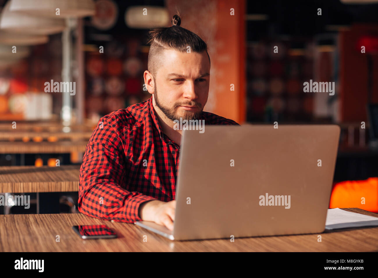 Hipster barbu travailler à un ordinateur portable dans un café Banque D'Images