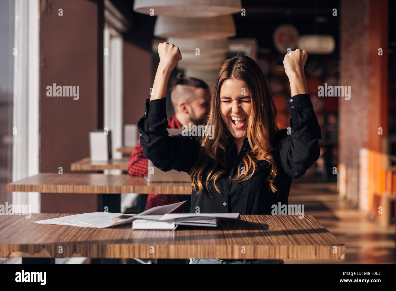 Cheerful young businesswoman en gardant les bras lever Célébrons les succès du cafe Banque D'Images