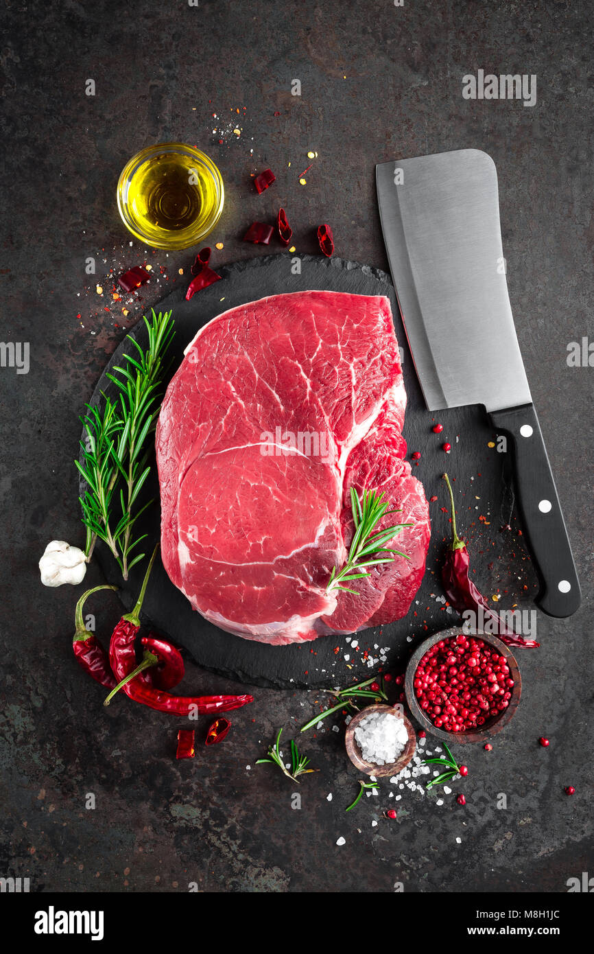 Steak de boeuf cru sur fond noir avec des ingrédients. La viande de boeuf fraîche. Vue d'en haut Banque D'Images