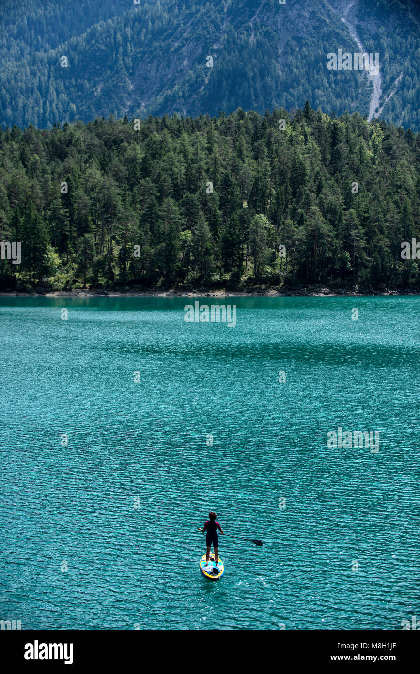 Une pagaie boarder sur Blindsee, un lac dans la région de Tyrol des Alpes autrichiennes. Banque D'Images